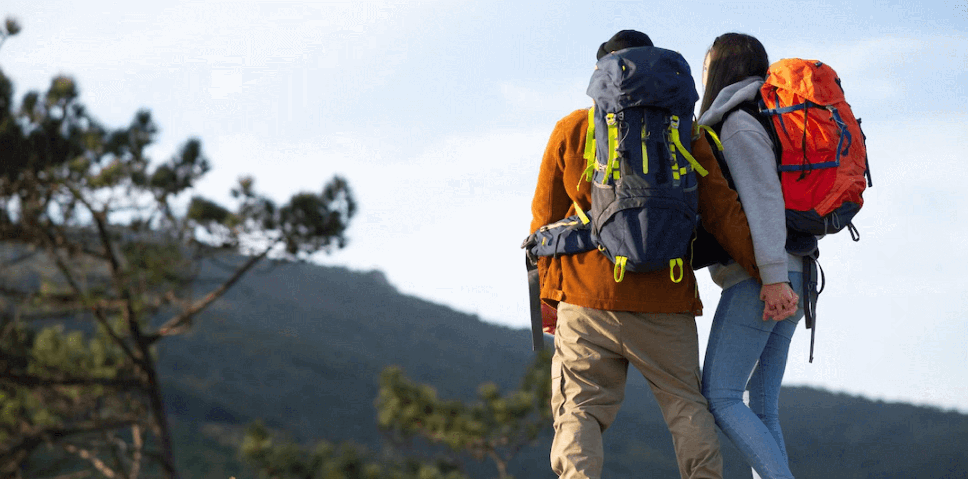 Two backpackers hiking up a rugged mountain trail wearing fully loaded multi-day backpacking packs.
